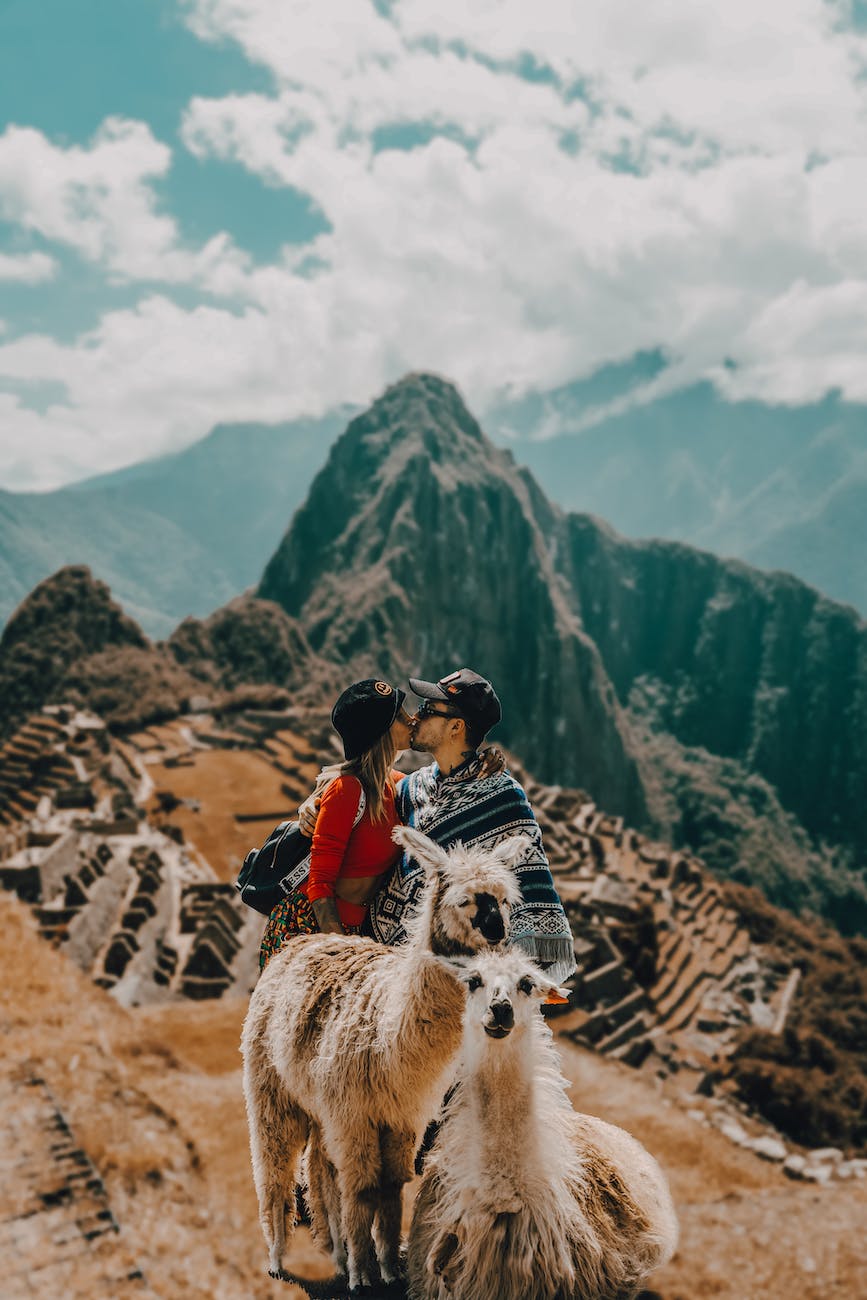 a couple standing on a mountain on the background of machu picchu and kissing