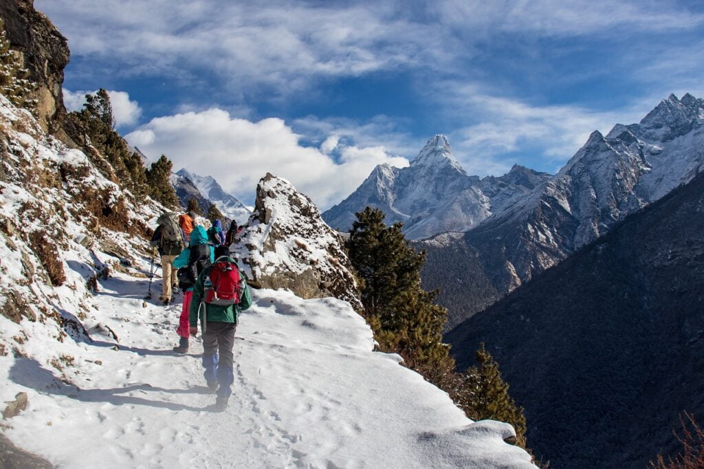 People trekking up a snowy mountain trail in Nepal, showcasing the beauty of nature and adventure in this top travel destination