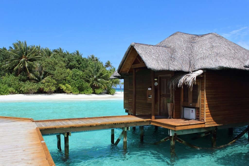 Crystal clear waters of the Maldives lap against a pristine sandy beach under a clear blue sky. 