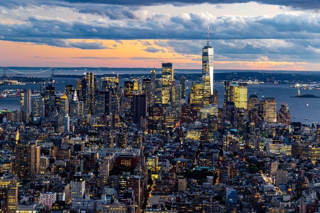 Enchanting dusk view of New York City skyline, featuring famous landmarks and dazzling lights.