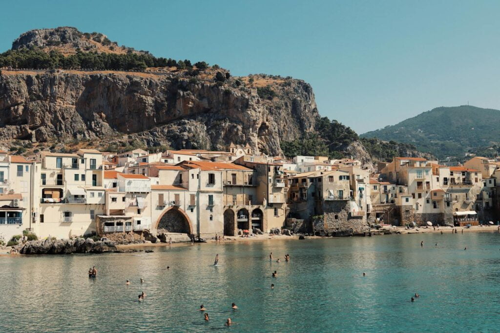 Aerial view of Sicily, Italy showcasing beautiful coastline, rolling hills, and historic architecture. best places to travel in may