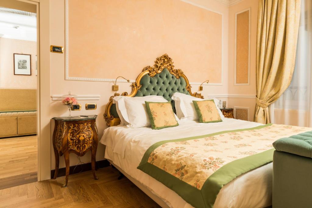 A cozy bedroom at Hotel Bernini Palace in Florence, Italy, featuring a bed with a stylish green headboard.