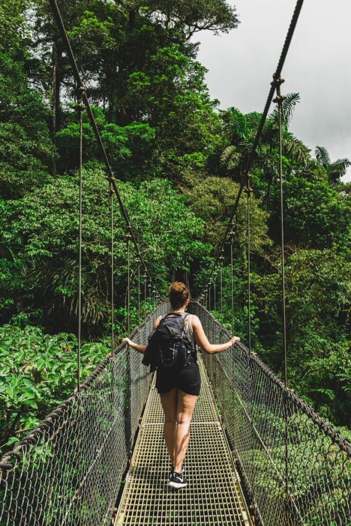 woman in black jacket and black pants standing on hanging bridge - Costa Rica Travel Guide