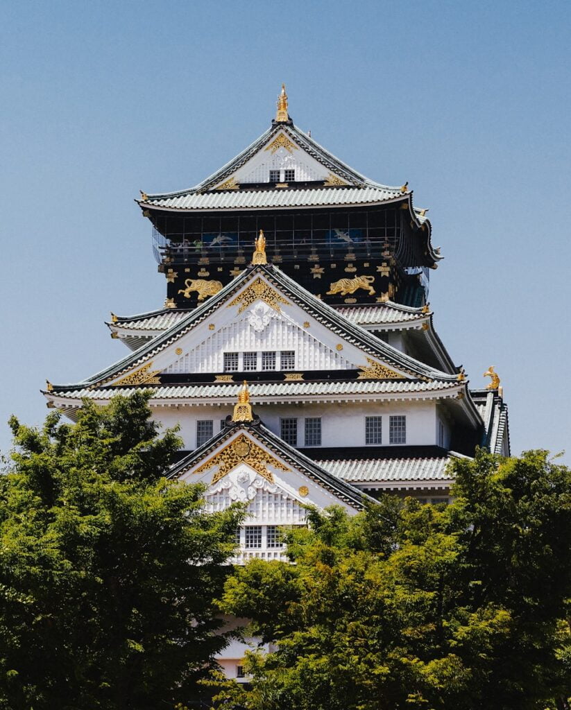 white and gold temple surrounded by green trees during daytime - Osaka Castle One of the best things to do in Japan