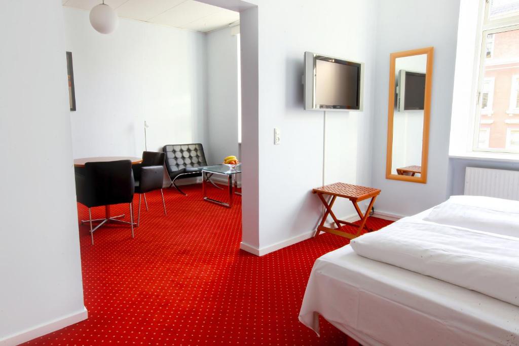 Luxurious hotel room with red carpet and white bed at Hotel Nora in Copenhagen.