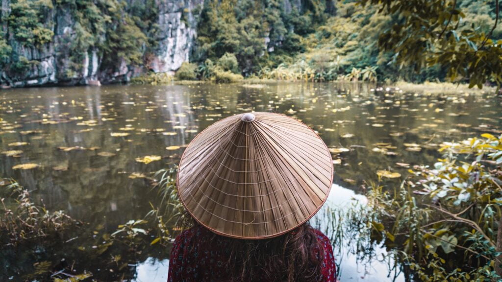 A woman in a hat gazes at a pond in one of Southeast Asia's top budget-friendly cities for solo travelers.