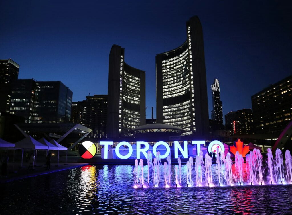 a city with a fountain and buildings - Toronto at Night