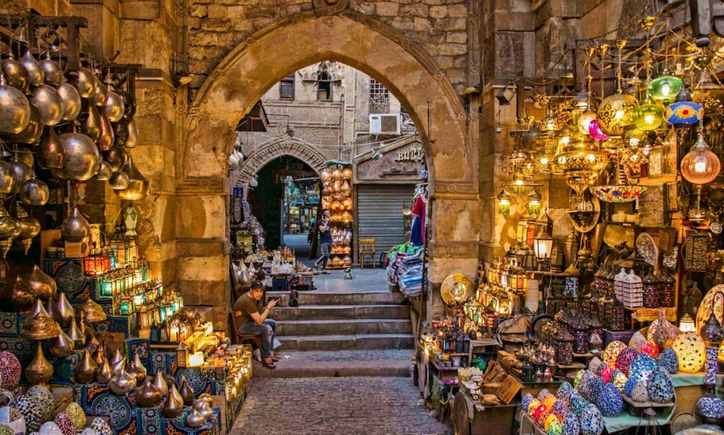 a narrow alley way with a lot of items on display
one of the things to do in cairo Khan El-Khalili Bazaar