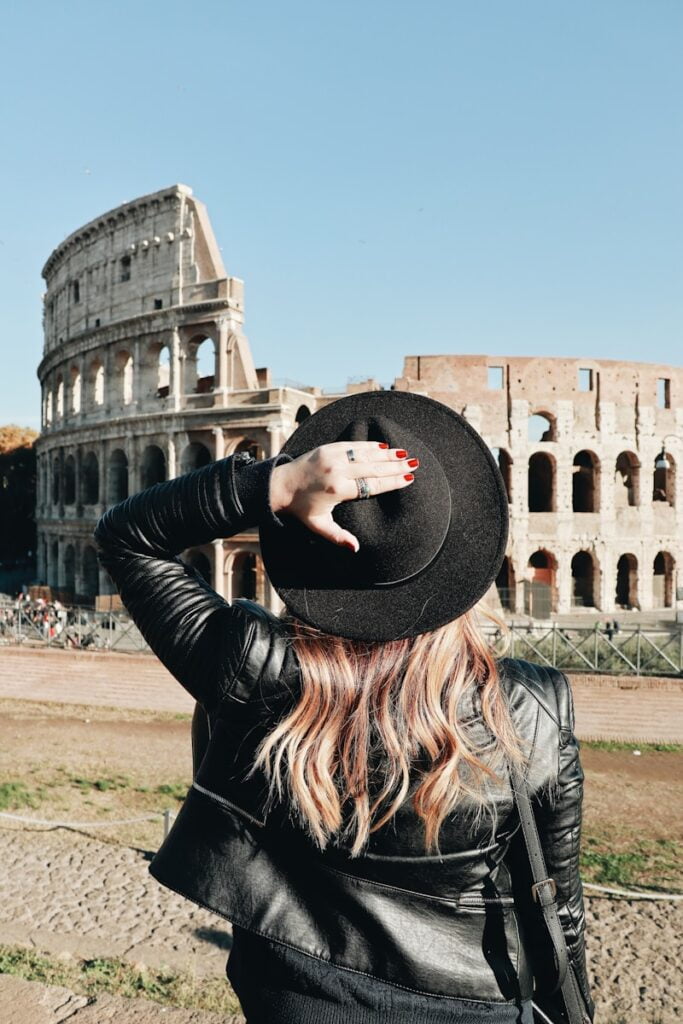 Woman in hat and black jacket admiring Colosseum in Rome, one of many budget solo travel destinations in Eastern Europe.