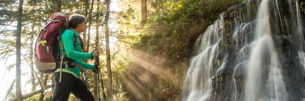 Woman with backpack by waterfall, part of top 10 hiking trails in Canada. Photo by parks.canada.ca.