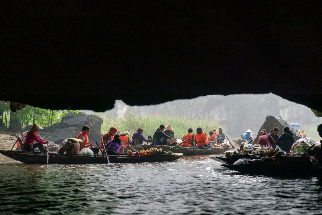 a group of people riding on top of a boat in Trang An Grottoes