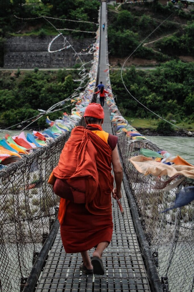 a person walking on a suspension bridge, Bhutan Tourism