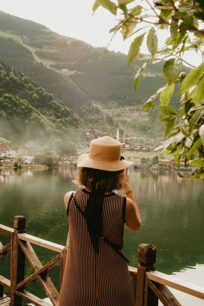 Woman in Hat Taking Pictures by Lake, Make Memories with a Travel Journal - best travel tips for beginners